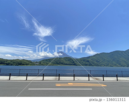 鼠色の道路の向こうに満杯の湖と紺碧の青空の下にそびえる群青色の富士山 136011311