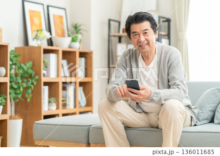 リビングでスマホを見るミドルの男性 リビングでスマホを見るミドルの男性 136011685