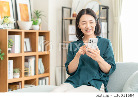 リビングでスマホを見るミドルの女性 リビングでスマホを見るミドルの女性 136011694