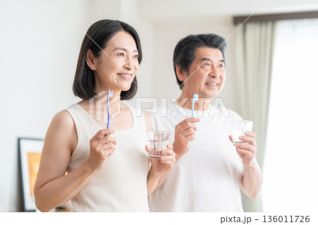 リビングで歯磨きをするミドルの夫婦 リビングで歯磨きをするミドルの夫婦 136011726
