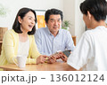リビングでスマホをみんなで見る家族 136012124