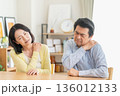 リビングで肩こりでマッサアージをするミドルの夫婦 136012133