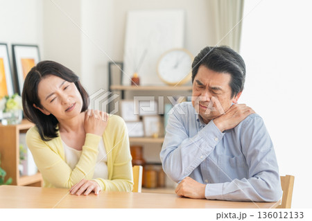 リビングで肩こりでマッサアージをするミドルの夫婦 リビングで肩こりでマッサアージをするミドルの夫婦 136012133