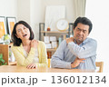 リビングで肩こりでマッサアージをするミドルの夫婦 136012134