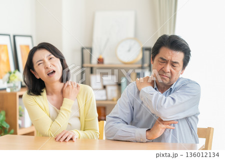 リビングで肩こりでマッサアージをするミドルの夫婦 リビングで肩こりでマッサアージをするミドルの夫婦 136012134