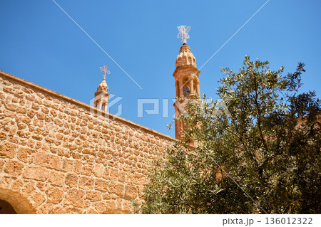 Stone church towers with crosses behind historic wall 136012322