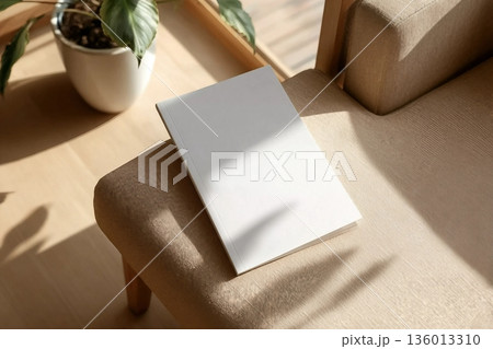 book cover mockup design. blank book template on soft beige armchair in living room or hotel room, shadow overlay book cover mockup design. blank book template on soft beige armchair in living room or hotel room, shadow overlay 136013310