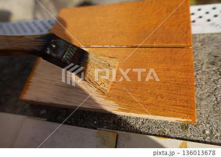 木材に塗料を塗る刷毛作業のクローズアップ　DIY塗装とメンテナンス 136013678