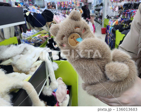 There are funny brown fur mittens shaped like capybaras on the store's shelf. There are funny brown fur mittens shaped like capybaras on the store's shelf. 136013683