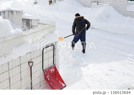 除雪スコップで雪かきをしているシニア男性の後ろ姿 136013684