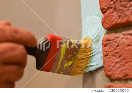 Outdoor wall painting by color brush. Handyman painting concrete block wall. 136015099