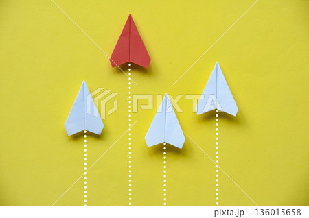 Red paper airplane leading white planes on yellow background illustrating leadership courage and direction Red paper airplane leading white planes on yellow background illustrating leadership courage and direction 136015658