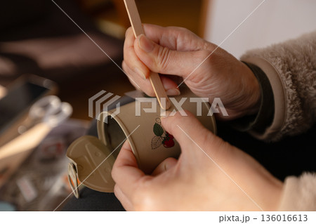 転写シールを白いリメ缶に貼っている女性の手元 136016613