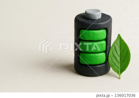 Eco-friendly battery made of plasticine with a green leaf. Space for text. 136017036