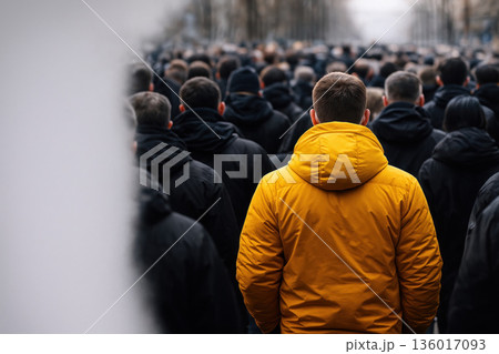 A man in a bright yellow jacket among a black crowd. Space for text. A man in a bright yellow jacket among a black crowd. Space for text. 136017093