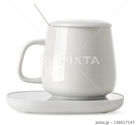 White ceramic mug set on electric warmer keeping drink hot 136017147