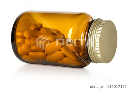 Amber glass bottle lying with orange pills 136017152