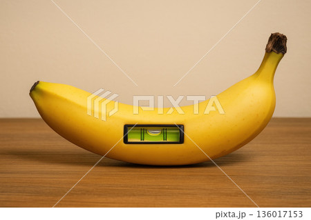 A yellow banana with a level inside on a wooden table. A yellow banana with a level inside on a wooden table. 136017153
