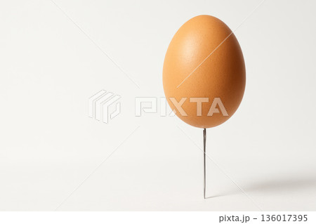 An egg on a sharp nail. Space for text. 136017395