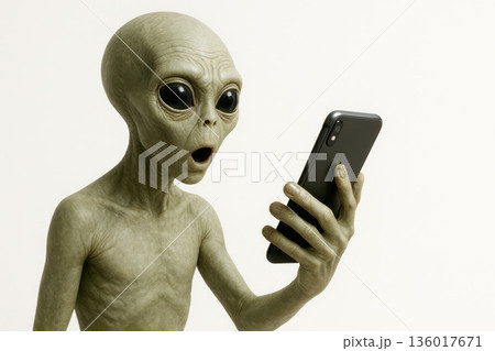 The alien looks at the smartphone in surprise. Space for text. 136017671