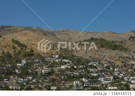 Hillside village landscape captured from the road in August 2025, showing traditional houses scattered across dry Mediterranean mountains under a calm summer sky. Hillside village landscape captured from the road in August 2025, showing traditional houses scattered across dry Mediterranean mountains under a calm summer sky. 136018151