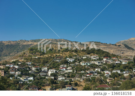 Hillside village landscape captured from the road in August 2025, showing traditional houses scattered across dry Mediterranean mountains under a calm summer sky. Hillside village landscape captured from the road in August 2025, showing traditional houses scattered across dry Mediterranean mountains under a calm summer sky. 136018158