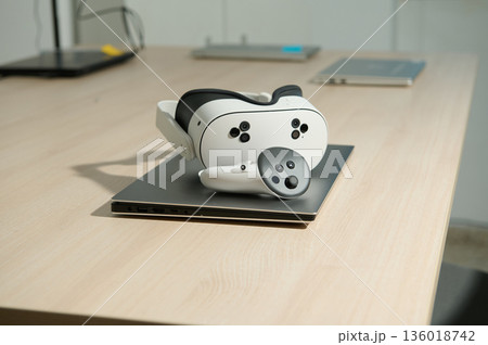 VR Headset Resting On Laptop On Wooden Desk In Modern Office Setting 136018742