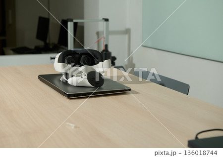 Virtual Reality Headset And Controller On Laptop In Modern Office or Classroom Setting Virtual Reality Headset And Controller On Laptop In Modern Office or Classroom Setting 136018744