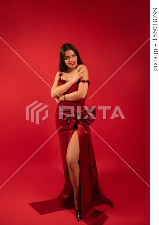 Beautiful woman in a red dress poses on a red background for a special occasion celebrating love and beauty 136018799