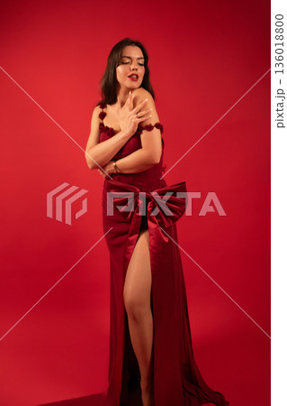 Woman in red dress posing against a red background for a Valentines Day themed shoot 136018800