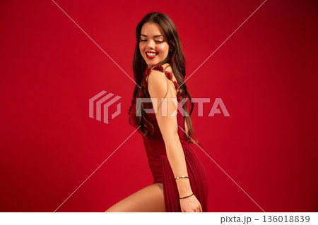 Woman in red dress smiles against red background for Valentines Day celebration while expressing joy and love Woman in red dress smiles against red background for Valentines Day celebration while expressing joy and love 136018839
