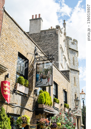 明るい日差しの下のパブの看板と植木で飾られた歴史的なレンガ造りの建物 ロンドン郊外のウィンザーにて 明るい日差しの下のパブの看板と植木で飾られた歴史的なレンガ造りの建物 ロンドン郊外のウィンザーにて 136019807