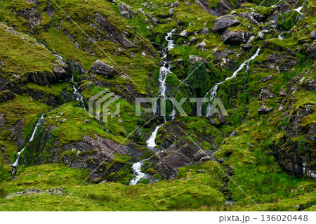 Verdant green slopes are streaked by glistening water courses. Verdant green slopes are streaked by glistening water courses. 136020448