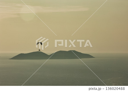 Mountain range rising above a calm blue sea under a clear sky, forming a minimalistic coastal landscape. Serene natural scenery captured on August 2025. Mountain range rising above a calm blue sea under a clear sky, forming a minimalistic coastal landscape. Serene natural scenery captured on August 2025. 136020488