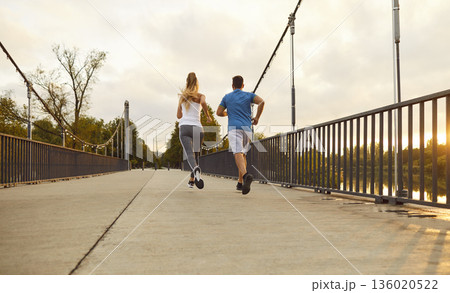 Couple jogging on park bridge at sunrise, rear view healthy outdoor fitness run 136020522