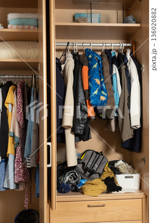 Open wooden wardrobe with casual clothes on hangers Open wooden wardrobe with casual clothes on hangers 136020882