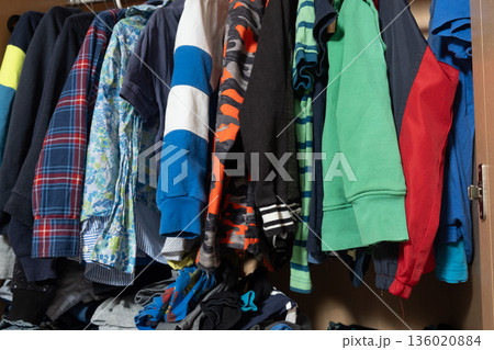 Organization of space in the wardrobe for childrens clothes, hanging sweaters on hangers in a wooden wardrobe Organization of space in the wardrobe for childrens clothes, hanging sweaters on hangers in a wooden wardrobe 136020884