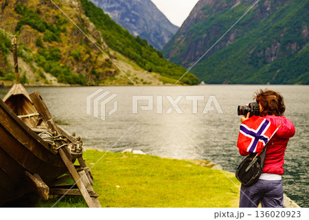 Tourist with camera near old viking boat, Norway Tourist with camera near old viking boat, Norway 136020923