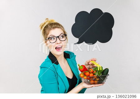 Woman holds shopping cart with vegetables, copy space Woman holds shopping cart with vegetables, copy space 136021096