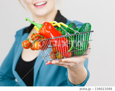 Woman holds shopping basket with vegetables Woman holds shopping basket with vegetables 136021098