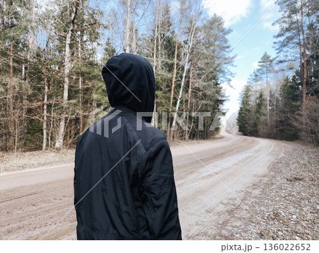 lonely man is walking on a forest path a hoodie. mental health concept. Hooded person walking lonely man is walking on a forest path a hoodie. mental health concept. Hooded person walking 136022652
