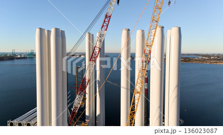Aerial view of wind turbine tower sections with cranes at port Aerial view of wind turbine tower sections with cranes at port 136023087