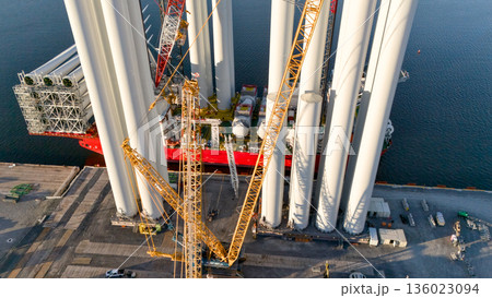 Aerial view of wind turbine towers loaded at port with heavy cranes Aerial view of wind turbine towers loaded at port with heavy cranes 136023094
