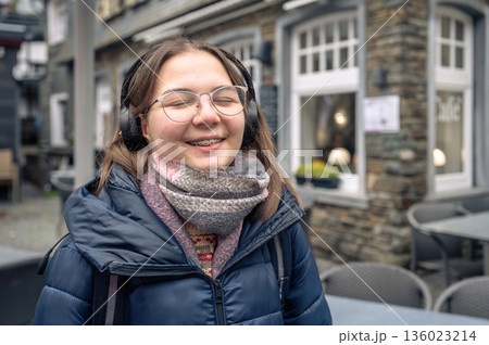 Smiling teenager girl with braces, eyeglasses and headphones Smiling teenager girl with braces, eyeglasses and headphones 136023214