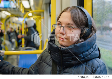 Smiling teenager girl with braces and headphones in tram during rainy weather Smiling teenager girl with braces and headphones in tram during rainy weather 136023227