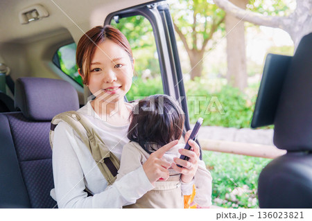 抱っこ紐で子供と一緒にタクシーに乗る女性 136023821