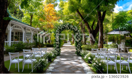 Enchanting Outdoor Wedding Ceremony Venue with Arch and Seating Surrounded by Lush Greenery and Sunlight 136023926