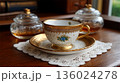 Elegant Vintage Tea Cup and Saucer Set with Gold Accents on a Doily 136024278