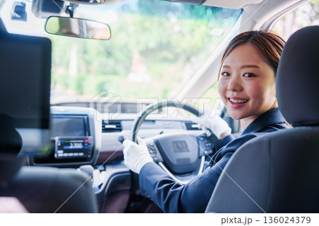 笑顔で運転をするタクシードライバーの女性 笑顔で運転をするタクシードライバーの女性 136024379