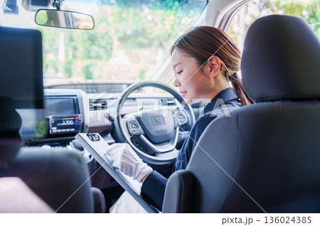 笑顔で運転をするタクシードライバーの女性 笑顔で運転をするタクシードライバーの女性 136024385